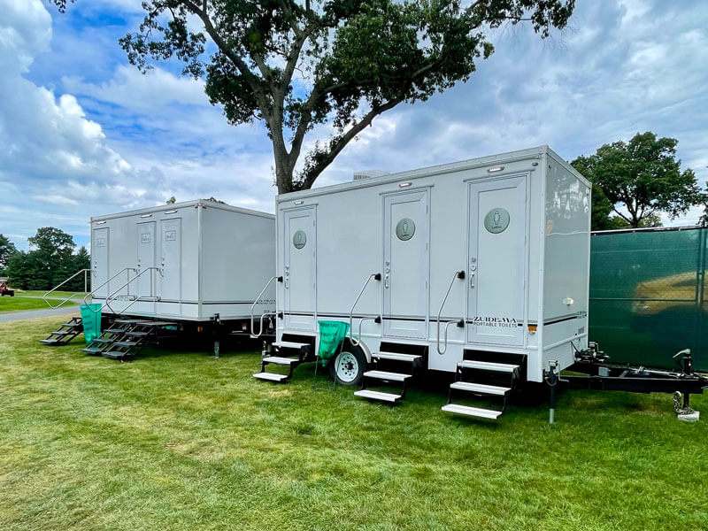 Two portable toilets on a trailer set in grass are available for rent in Orange County, NY
